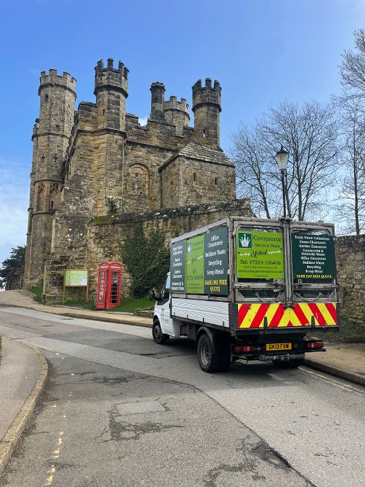 Conqueror Refuse & Waste collection vehicle parked near historic stone building in Hastings offering trade and garden waste services